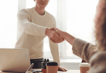 Photo of two professionals shaking hands after one of them accepts a job offer.